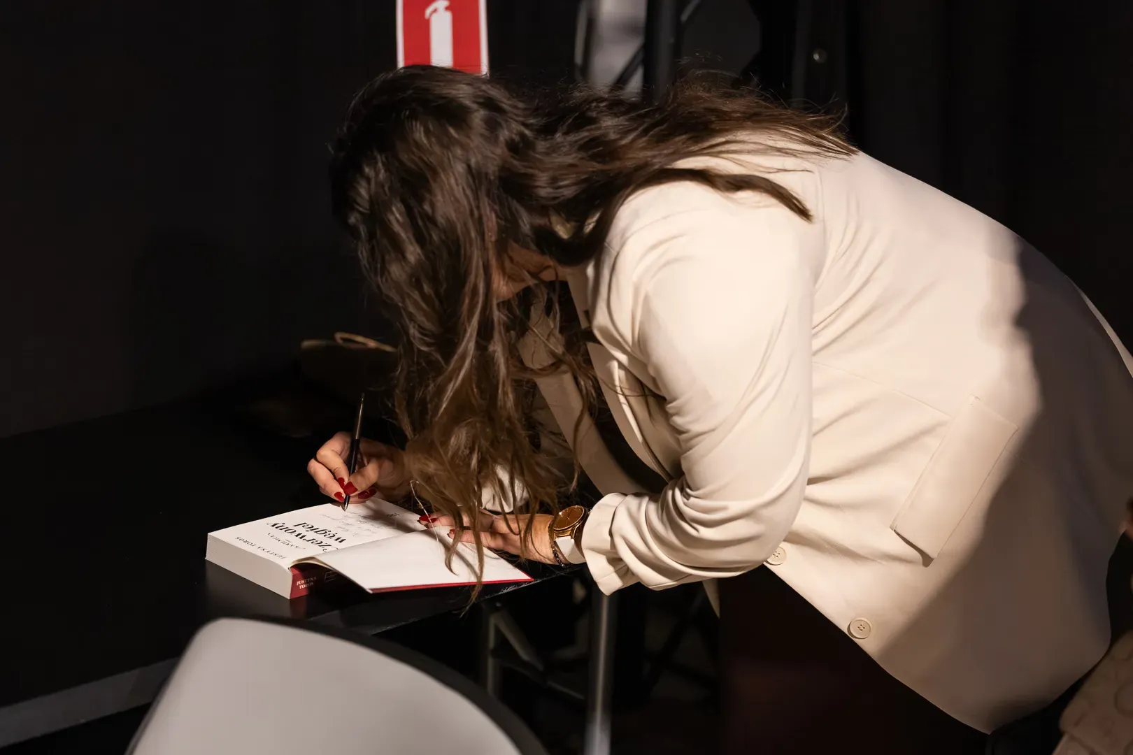 Justyna Toros wpisuje dedykację do książki